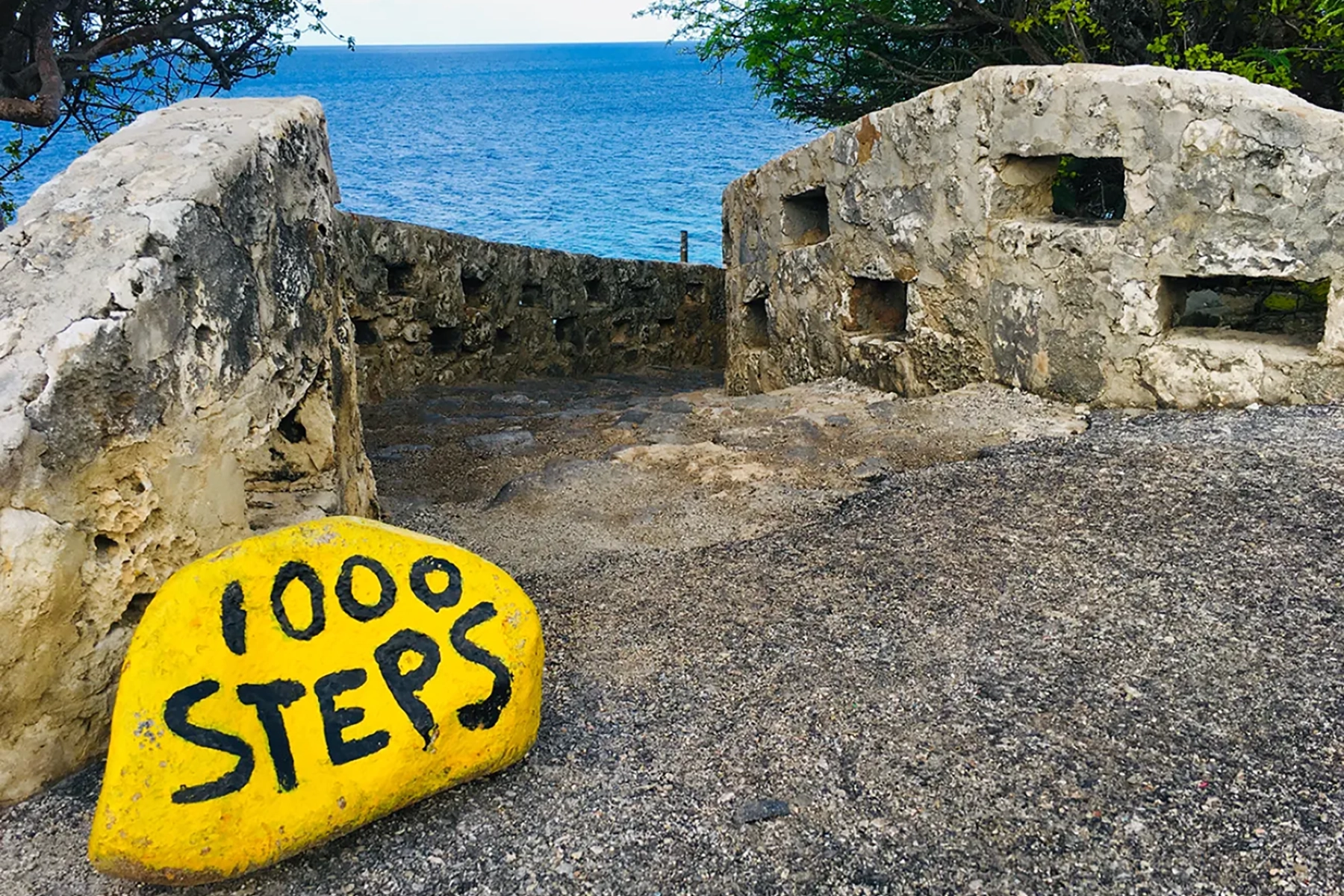 Yellow Hilma Hooker stone on a white-sand road near a well-known wreck dive site on Bonaire